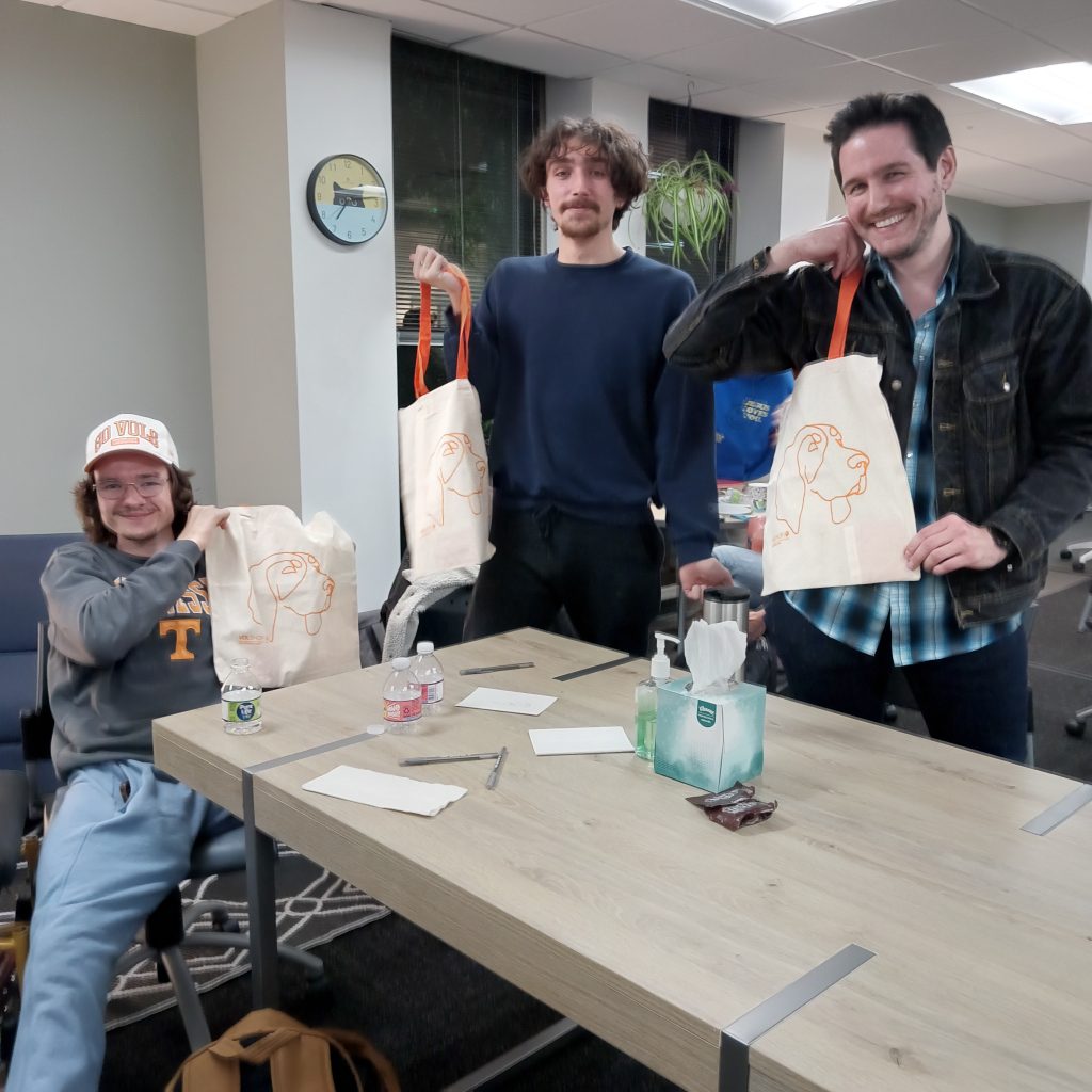 Three second-place winners hold up tote bags.